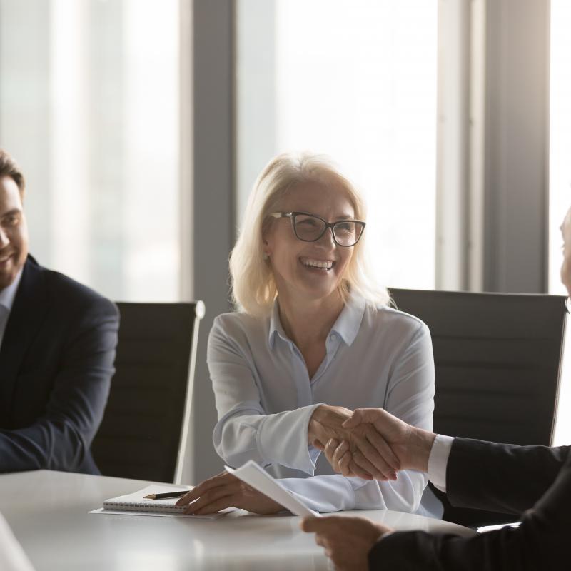 Happy,mature,businesswoman,handshaking,new,male,partner,,ceo,and,smiling